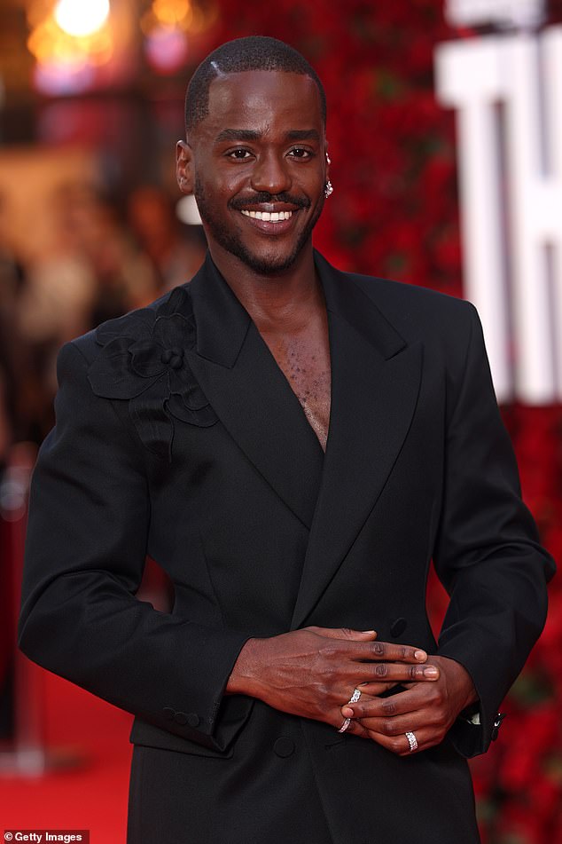 The star beamed as he went shirtless beneath his black blazer