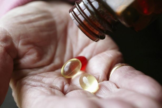 Elderly woman pouring vitamin pills on hand
