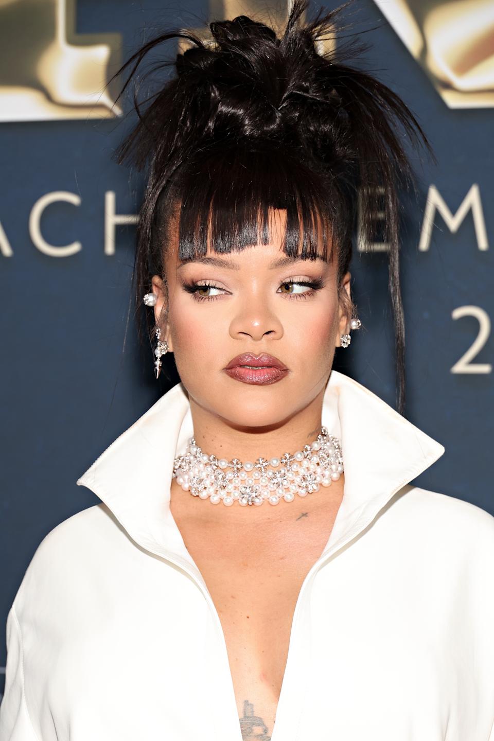 Rihanna in an elegant outfit with high collar and sparkling choker on a formal event background with her hair styled up, wearing earrings