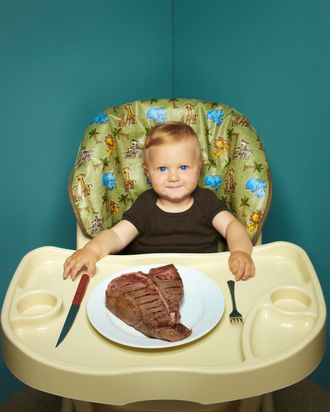 Child in high chair with T Bone steak.