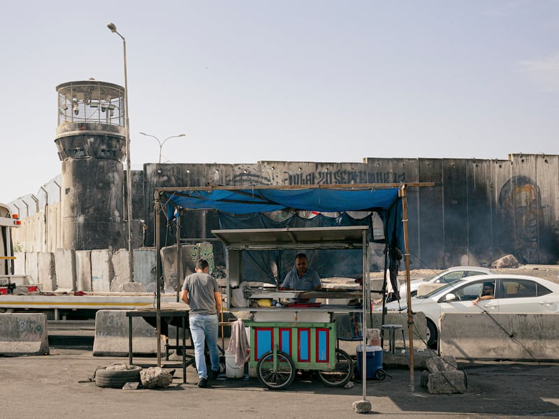 A vendor near a checkpoint where Palestinians sometimes wait all day trying to cross in Qalandia, West Bank. Photograph: William Keo/The New York Times
                      