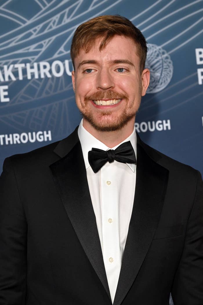 Mr Beast in a classic tuxedo with a bow tie poses on the red carpet at a formal event