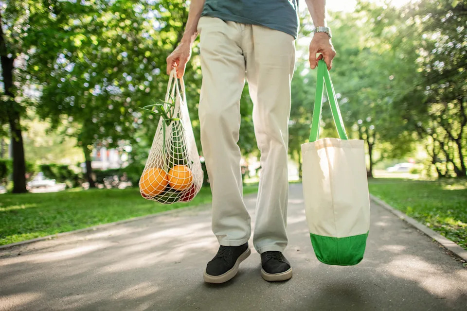 Senior man carrying fruits and vegetables in reusable shopping bag and mesh bag, environment conservation and sustainability concept