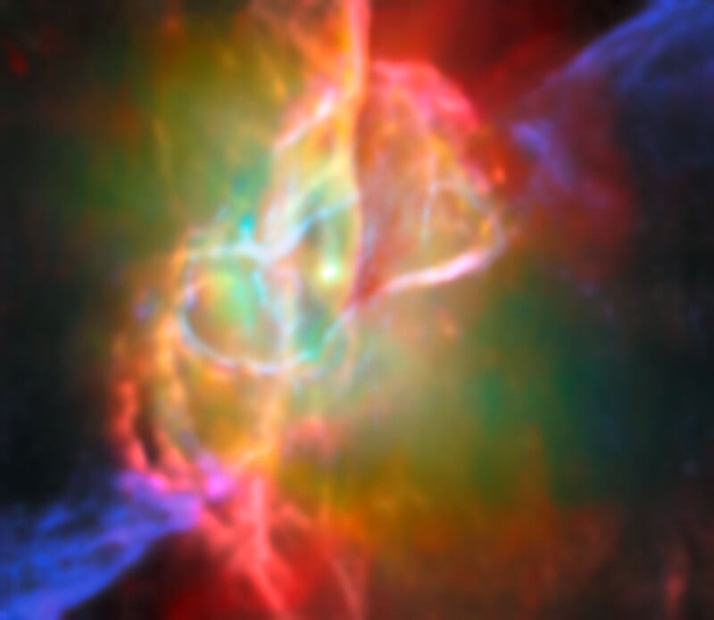 A vibrant, colorful image of a nebula in space, with swirling clouds of red, blue, green, and yellow gases blending together, creating a glowing, ethereal effect against a dark background.
