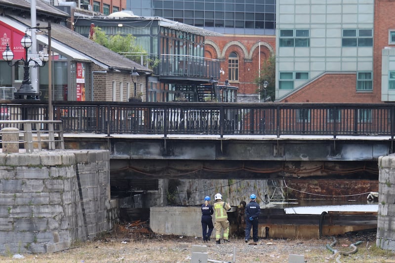 Gardaí and Dublin Fire Brigade personnel inspect the damaged George's Dock Bridge after a fire overnight. Photograph: Ronan McGreevy