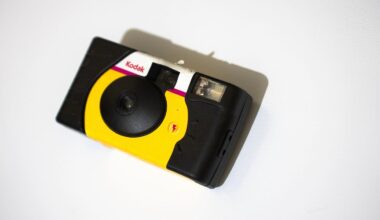 A Kodak disposable film camera with a yellow and black body and red accents, placed on a white surface, viewed from above.