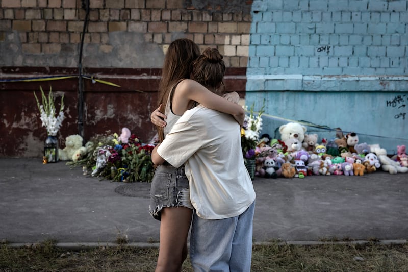 Two teen girls embrace in Kyiv on Friday as they view an impromptu memorial for those killed in by Russian missiles and drones the day before. Photograph: Finbarr O'Reilly/The New York Times
                      