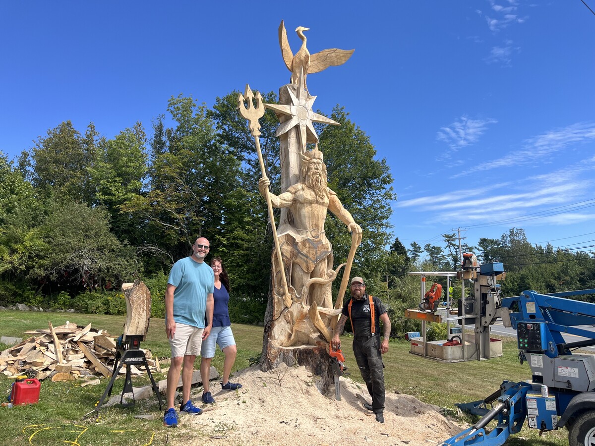 A chainsaw artist is carving Poseidon outside a Searsport motel