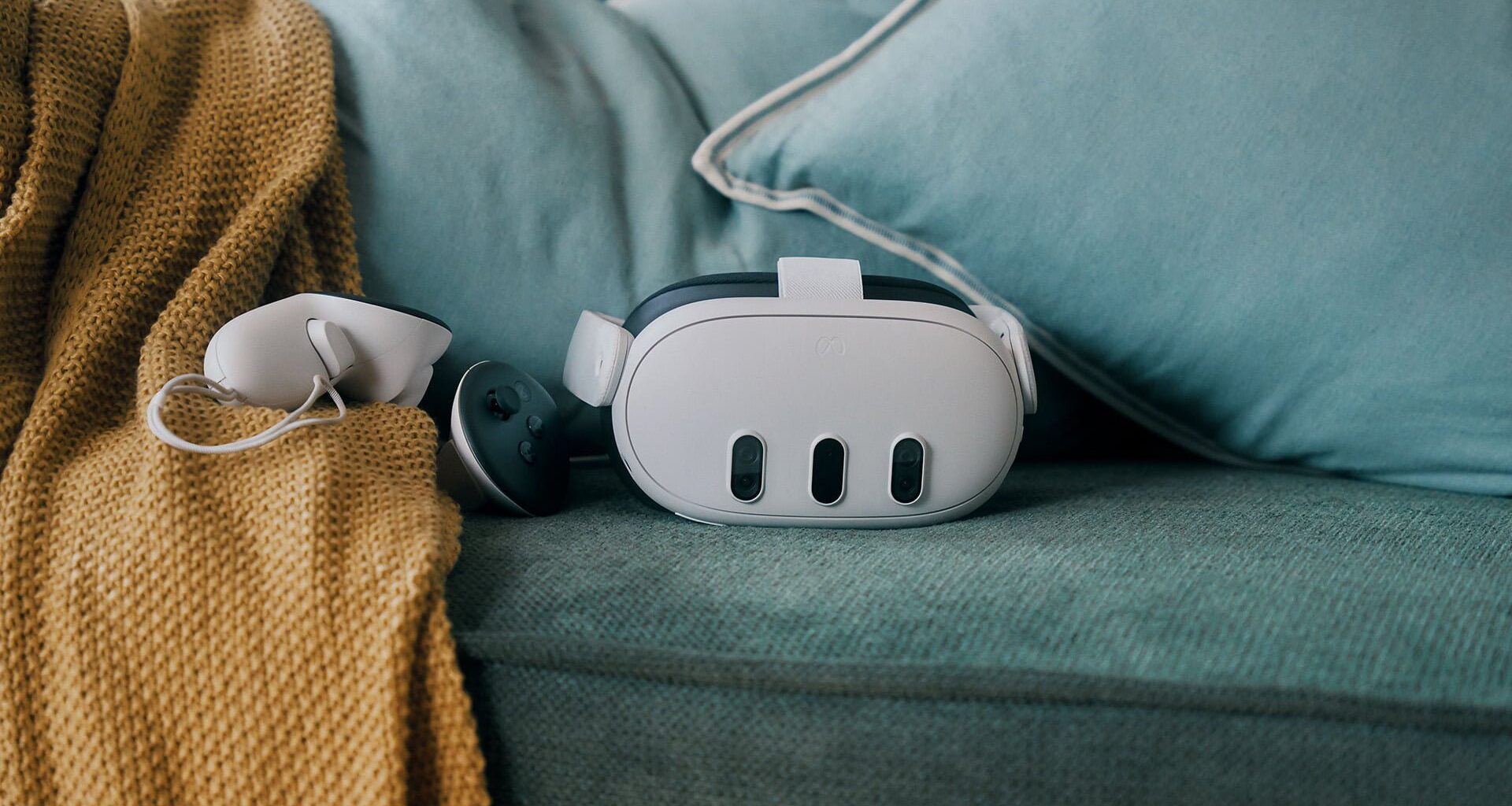 The Meta Quest 3 headset rests on a green couch alongside a controller.