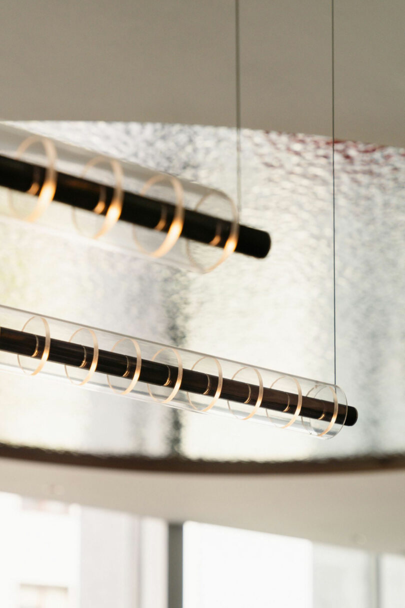 Two modern pendant light fixtures with cylindrical glass shades and visible spiral filaments hang from the ceiling in a contemporary interior space.
