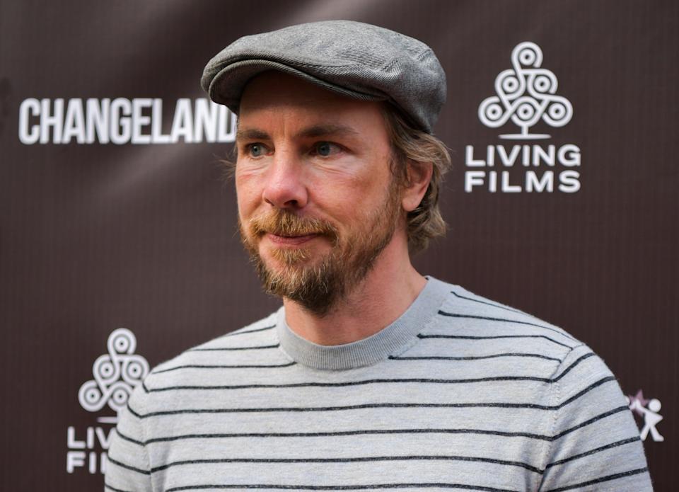 Dax Shepard in a striped shirt and flat cap at a film event backdrop with "Changeland" and "Living Films" logos