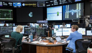 Two women sit at their desk in the Mission Control Center