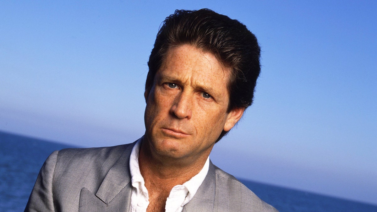 A close-up of Brian Wilson wearing a grey blazer and white shirt on the beach.