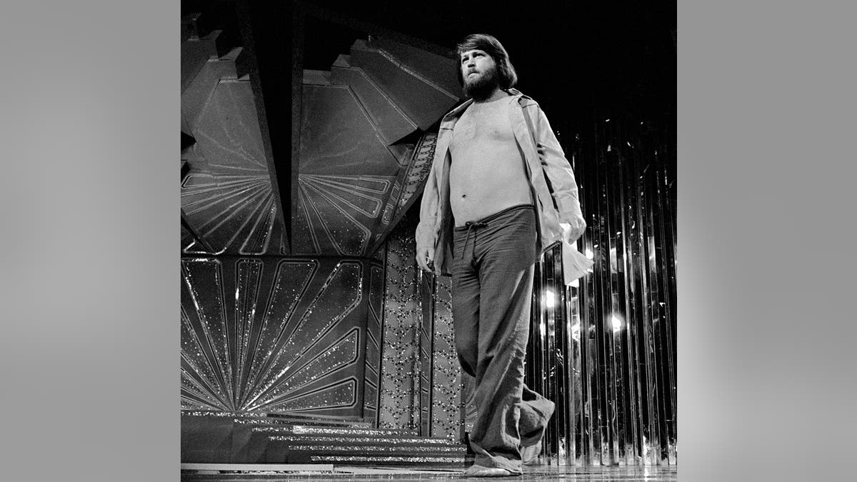 Brian Wilson walking on stage with his shirt wide open.