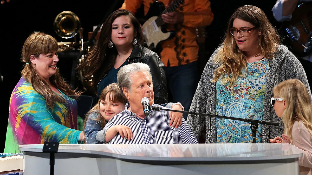 Brian Wilson performing on stage surrounded by his family.