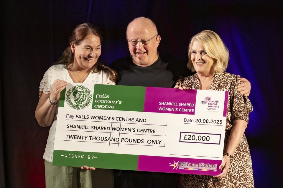 Betty Carlisle from the Shankill Women’s Centre and Suzanne McCrory from the Falls Women’s Centre receive a donation on behalf of Féile from Christy Moore during cross cross-community fundraiser for Shankill and Falls Women’s Centres on August 20th 2025 (Photo by Kevin Scott)