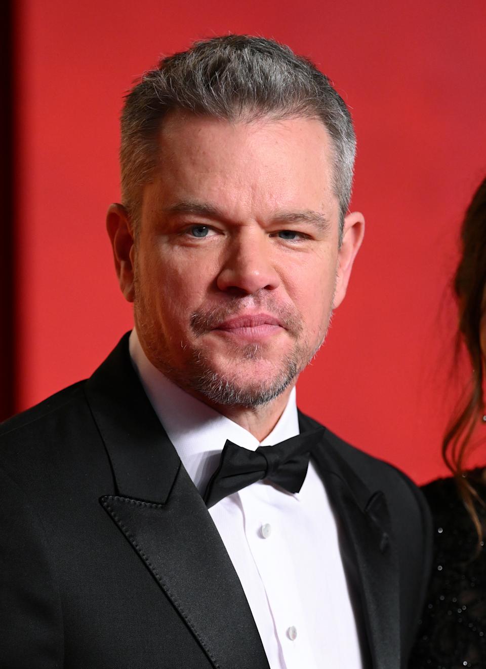 Matt Damon in a classic tuxedo and bow tie posing on a red carpet