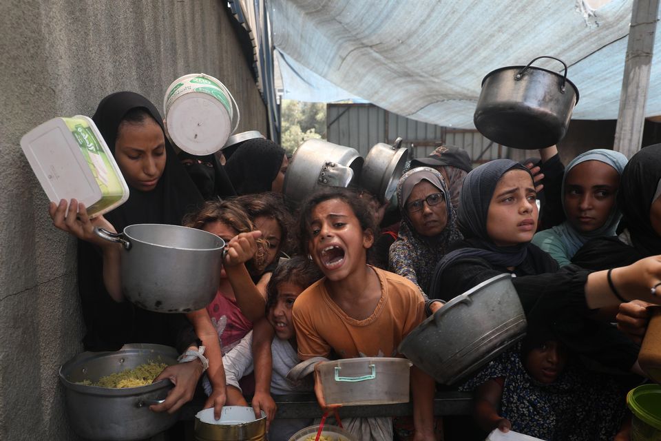 Palestinians, including children, plead for food as they wait for hot meals. Photo: Getty Images