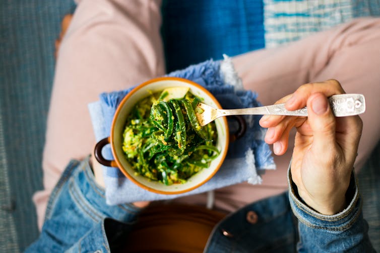 top shot of woman holding seaweed dish eating with fork