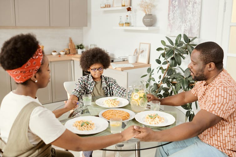 A family around a table holding hands