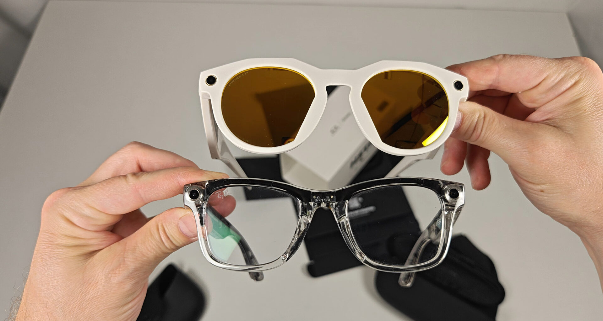 Comparing the front of the warm white Oakley Meta HSTN with transparent Ray-Ban Meta Smart Glasses