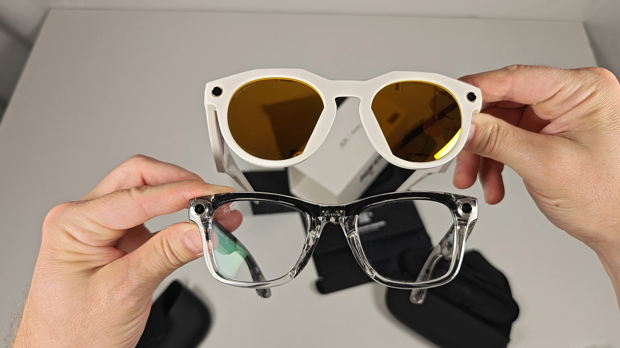 Comparing the front of the warm white Oakley Meta HSTN with transparent Ray-Ban Meta Smart Glasses
