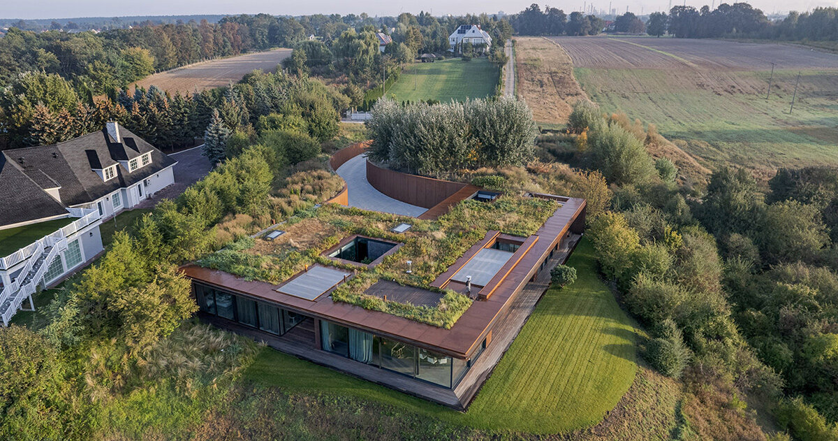 77 studio's 'house on the slope' camouflages beneath meadowed green roof in poland