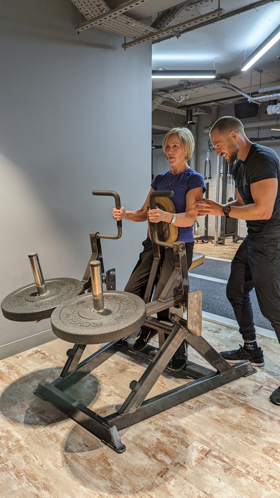 woman using gym equipment with personal trainer woman using gym equipment with personal trainer