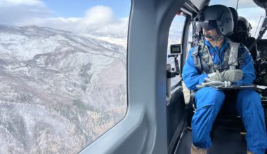 An astronaut in a helicopter looks out the window in their