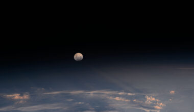 The Moon looks nearly full from the viewpoint of the International Space Station. Below, we can see the Moon's light being refracted by Earth's atmosphere. A few clouds can be seen at the bottom of the image.