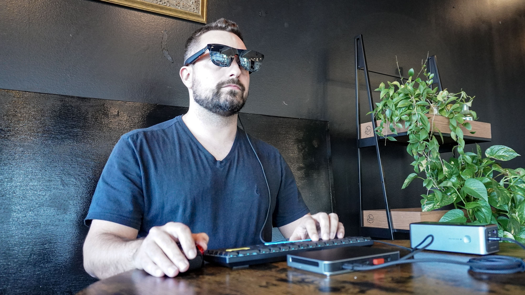 A person using Xreal One AR glasses with the Khadas Mind 2S mini PC at a coffee shop