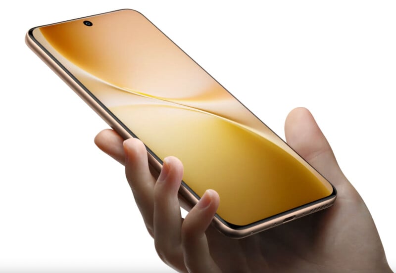 A hand holding a modern smartphone with a slim design and gold-colored edges, displaying a golden abstract wallpaper on its screen.