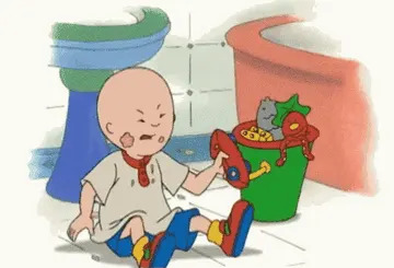 Cartoon child sits on the floor, wearing a white shirt and blue pants, holding a shoe, near a toy-filled bucket in a bathroom setting