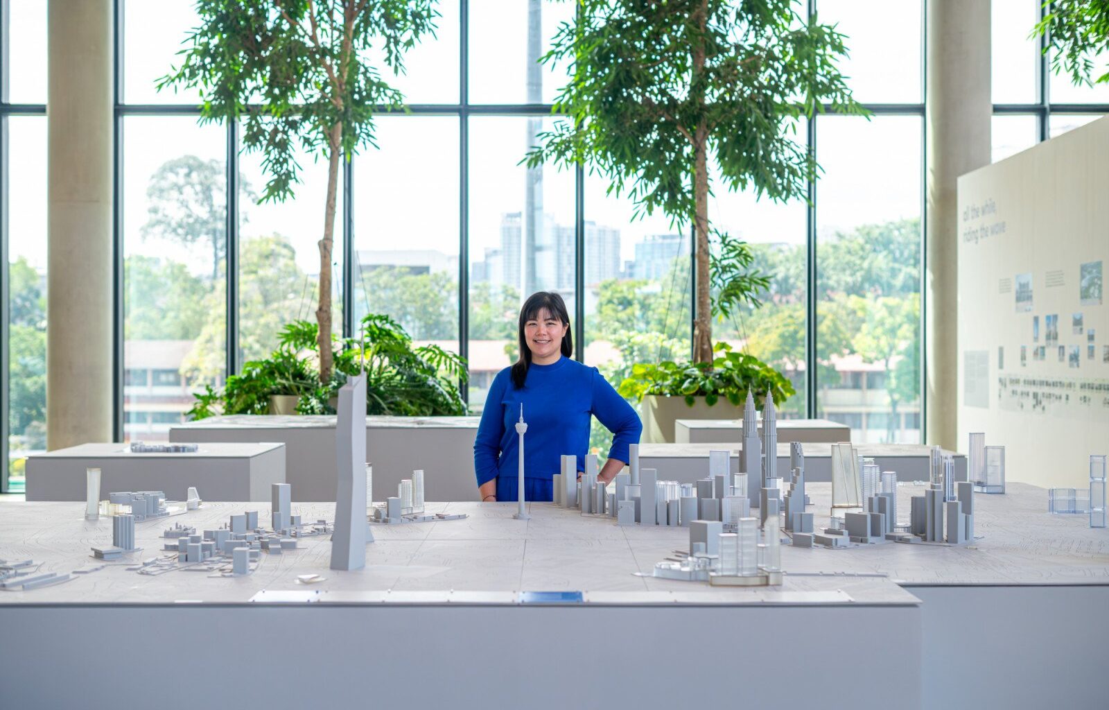 Sarah Merican, Partner at GDP Architects, stands beside a detailed architectural model of Kuala Lumpur’s skyline at the “group, design, partnership” exhibition, showcasing the firm’s contribution to Malaysian architecture over 35 years of practice at GDP Campus