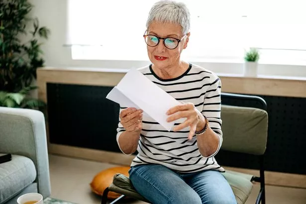 Portrait of a senior woman at home checking a letter in the mail while sitting in the living room