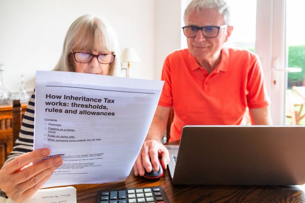 A couple in their 70s study inheritance tax documents while sitting down at a table