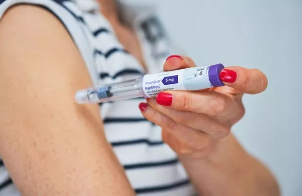 A woman injects herself with a Mounjaro pen