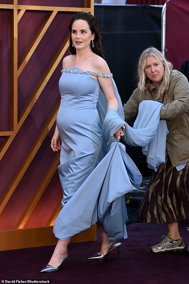 Michelle walked the red carpet in a powder blue off-the-shoulder gown with a fitted bodice as she showed off her bump