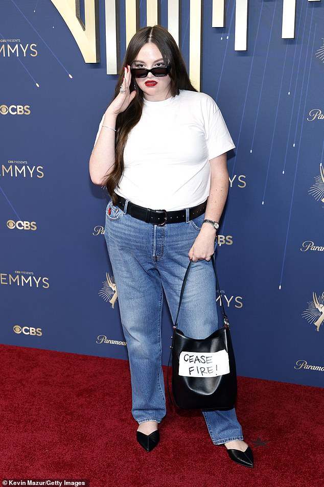 Megan Stalter, 34, who rose to fame in HBO Max comedy Hacks and Lena Dunham's Too Much, appeared to make a political statement with her very underwhelming ensemble of blue jeans, white T-shirt and black ballet flats - before adding the message 'cease fire' to her handbag