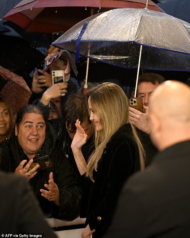 Braving the rain while sheltering under an umbrella, Angelina met a number of fans and posed for selfies