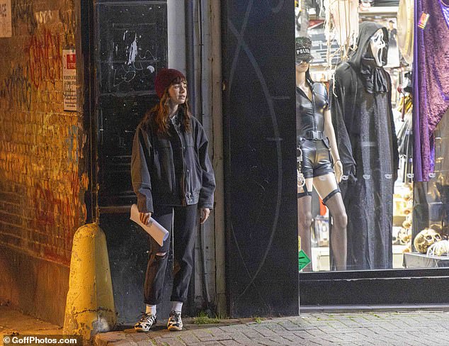 Lily leaned against the wall with papers in her hand between takes at the seedy backstreet