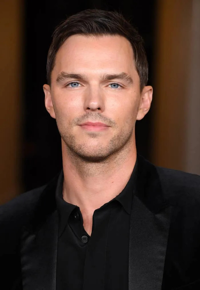 Nicholas Hoult in formal attire on the red carpet, looking towards the camera