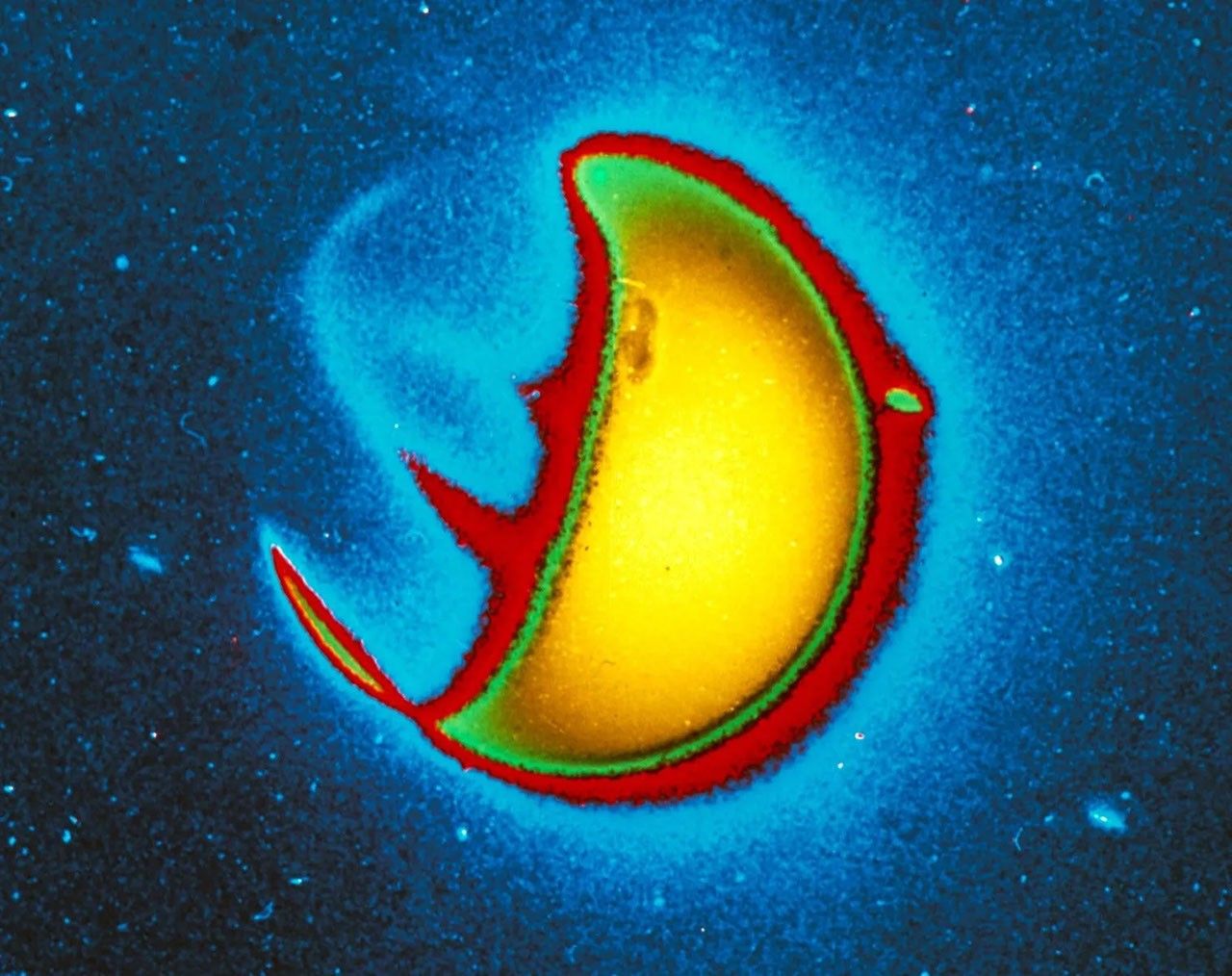 A false-color, close-up image of Earth’s exosphere as captured by the Carruthers Geocorona Observatory against a dark blue background. The image shows a semicircle glowing yellow and outlined in red.