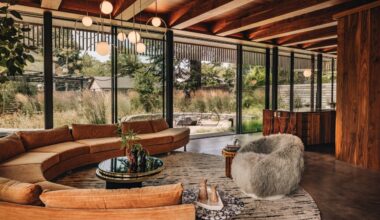 The living area in this Portland house features the reupholstered Milo Baughman sofa, Studio SORS lounge chair covered in New Zealand sheepskin, and Pablo chandelier above the concrete floors with metal veining