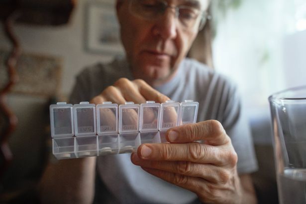 A man taking pills out of a medication box