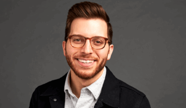 George Kamel smiling at the camera with a grey background