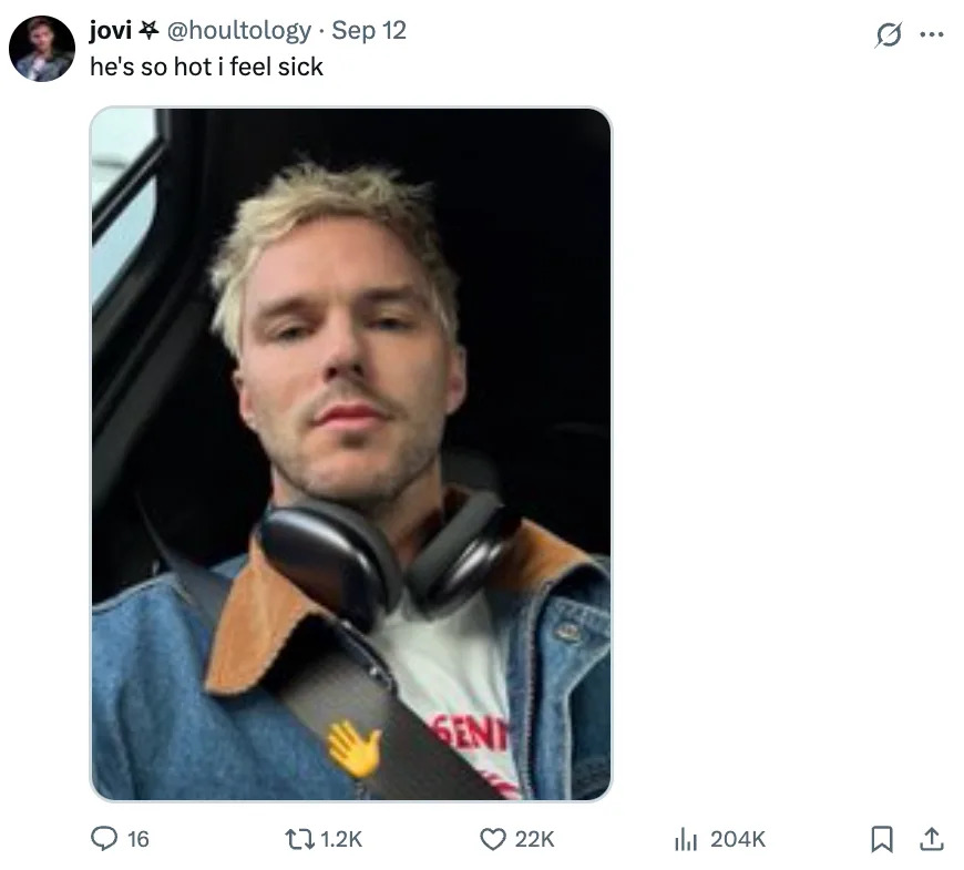 Nicholas Hoult with short hair in a casual jacket is in a car, wearing large headphones