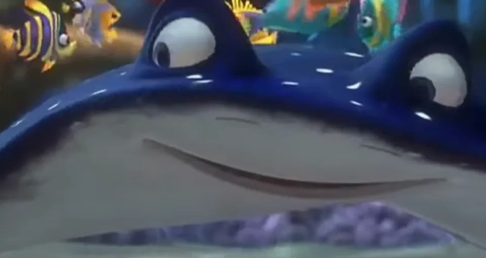Animated scene with a smiling stingray surrounded by colorful fish, likely from an animation movie