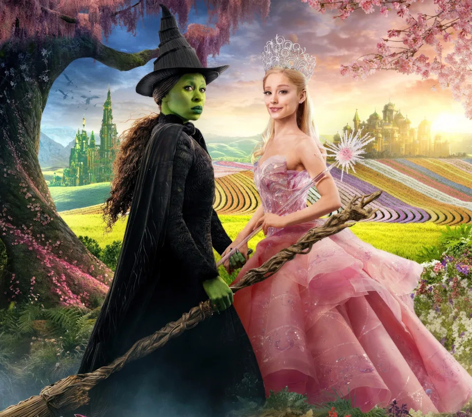 Two characters from "Wicked" stand outdoors. One wears a witch costume with a hat, the other a pink gown with a tiara. Text: "Only in Cinemas."