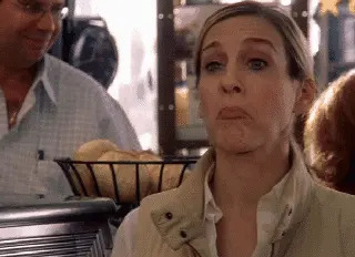 Person in cafe raising eyebrows, with a slight smirk, standing by a basket of bread rolls